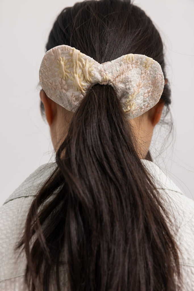 Flødefarvet scrunchie med stor sløjfe og let gyldent mønster
