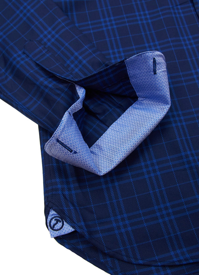 A close-up of the Anoka shows its blue plaid fabric, contrasting light blue inner cuff with stitching, buttonhole, and a small round logo tag.