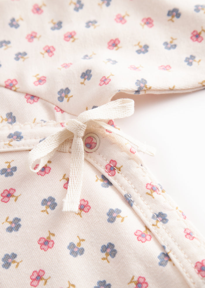 Langærmet bodystocking for a newborn baby with snap closure and flowers.