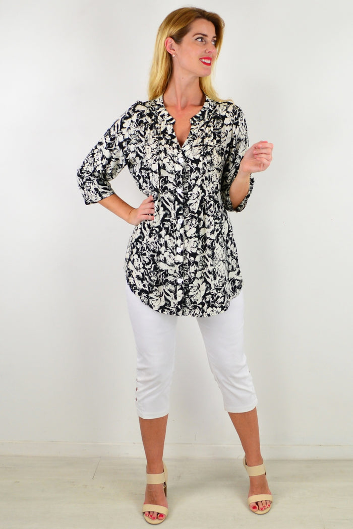 Black Roxanne floral tunic shirt by I Love Tunics, featuring a flowy fabric and vibrant floral pattern, displayed on a hanger.