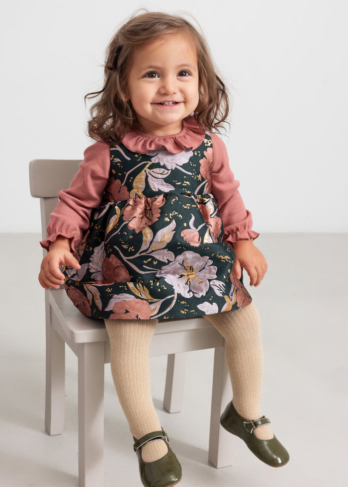 Baby wearing dusty pink bodysuit and floral print dress