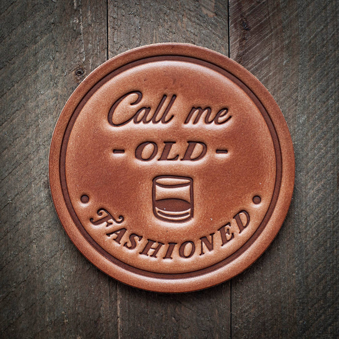 Brown leather coaster with Call me Old Fashioned text.