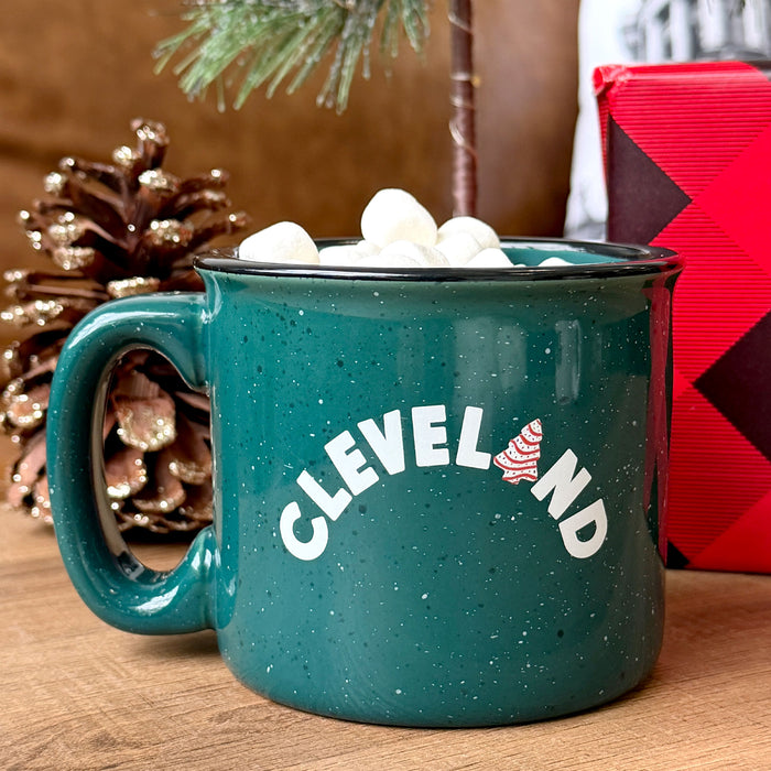 Teal mug with 'CLEVELAND' text and American flag design, filled with hot chocolate and marshmallows, on a wooden surface.