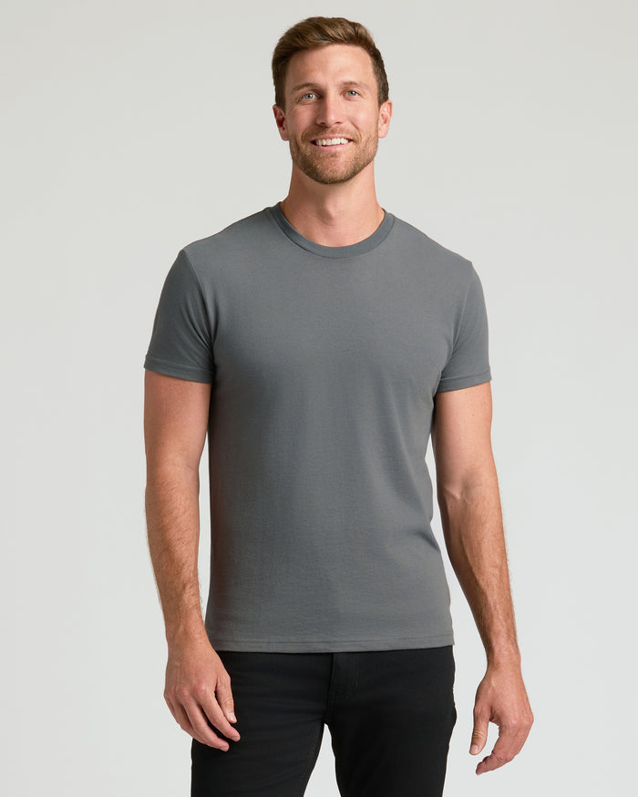 Man wearing Classic Crew Neck 6-Pack T-shirt, smiling against plain background.