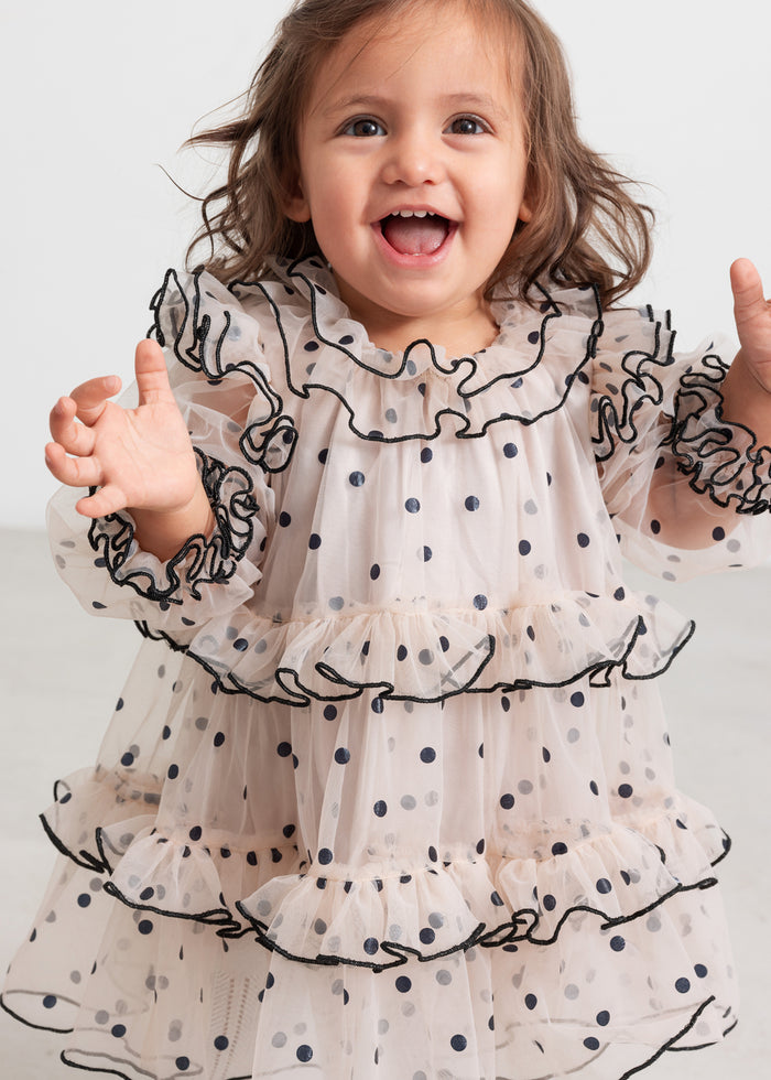 Baby wearing pink Christmas dress in tulle with black dots and ruffles