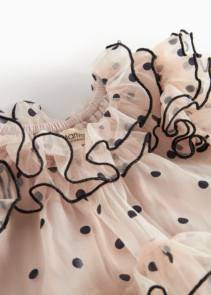 Close-up of pink tulle dress for children with black dots and wavy ruffled edges