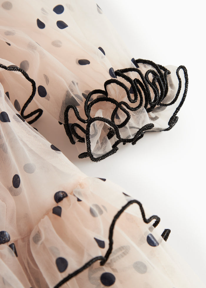 Close-up of pink tulle dress for children with black dots and wavy ruffled edges