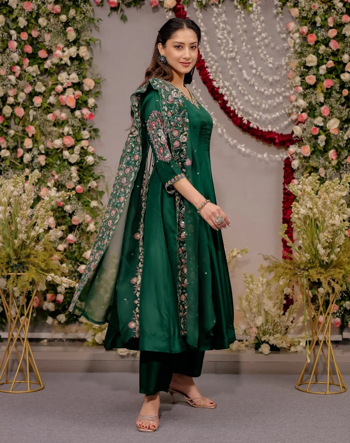 Woman in a green traditional outfit standing in front of floral decorations
