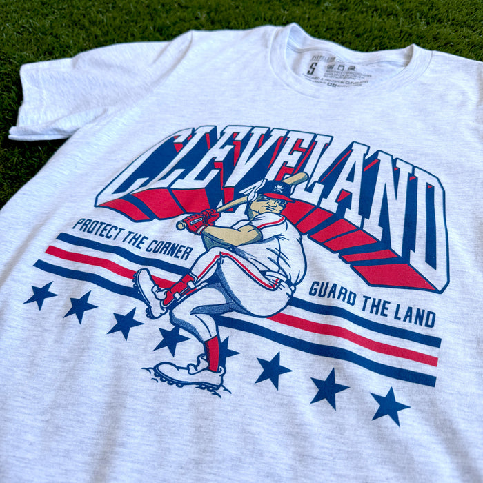 White t-shirt with a graphic design featuring a baseball player and text on a grass background