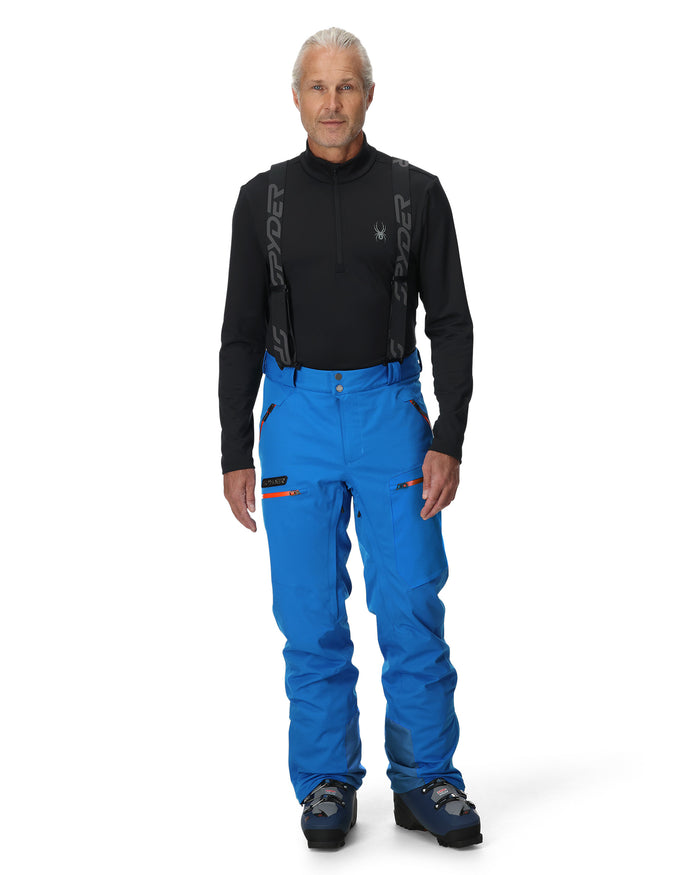 Man wearing a black top and blue pants on a white background