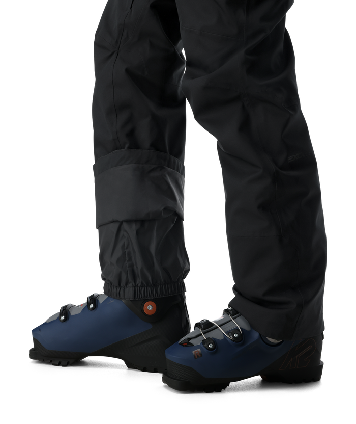 Blue ski boots with black pants on a white background
