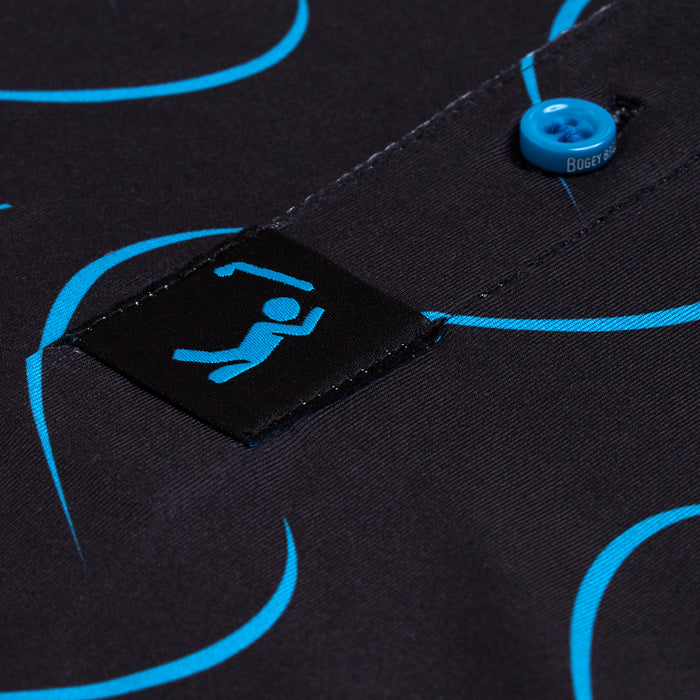 Close-up of the black, moisture-wicking Natural Slice - Polo fabric with bright blue curved lines, a rectangular black label featuring a blue stick figure raising both arms, and a blue button partially showing "BOGEY" in white on its edge.