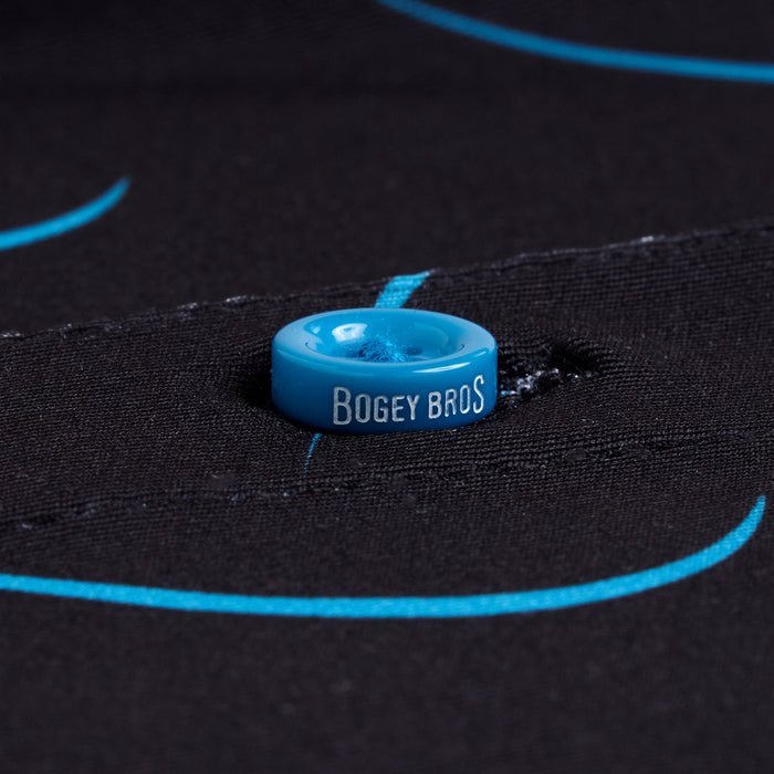 A close-up of a blue button with BOGEY BROS on it, sewn onto the black, light blue-lined fabric of the Natural Slice - Polo. The athletic fit provides style and comfort, perfect for active days.