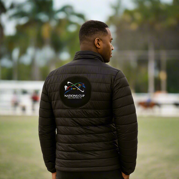 man wearing a black puffer jacket with jumping Nations Cup logo on the back outside