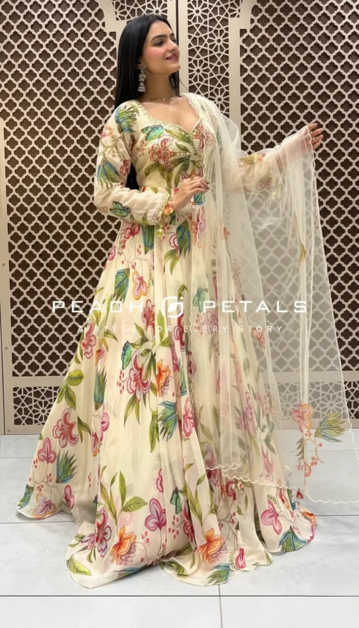 Cream-colored Indo-Western gown featuring vibrant pastel floral prints, long sleeves, and a matching sheer scalloped dupatta.