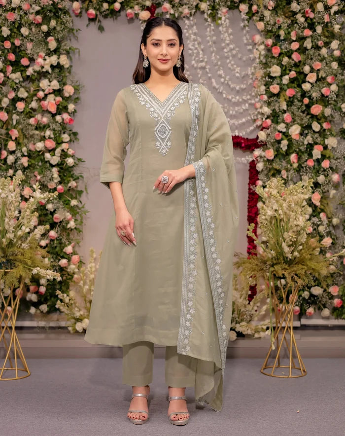 Woman in a light green traditional outfit with floral decorations in the background