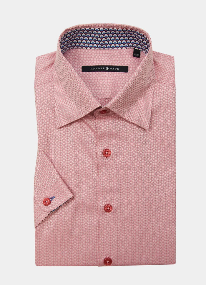The Waite shirt is a folded long-sleeve dress shirt in a pink pattern with red buttons and a contrasting inner collar detail.