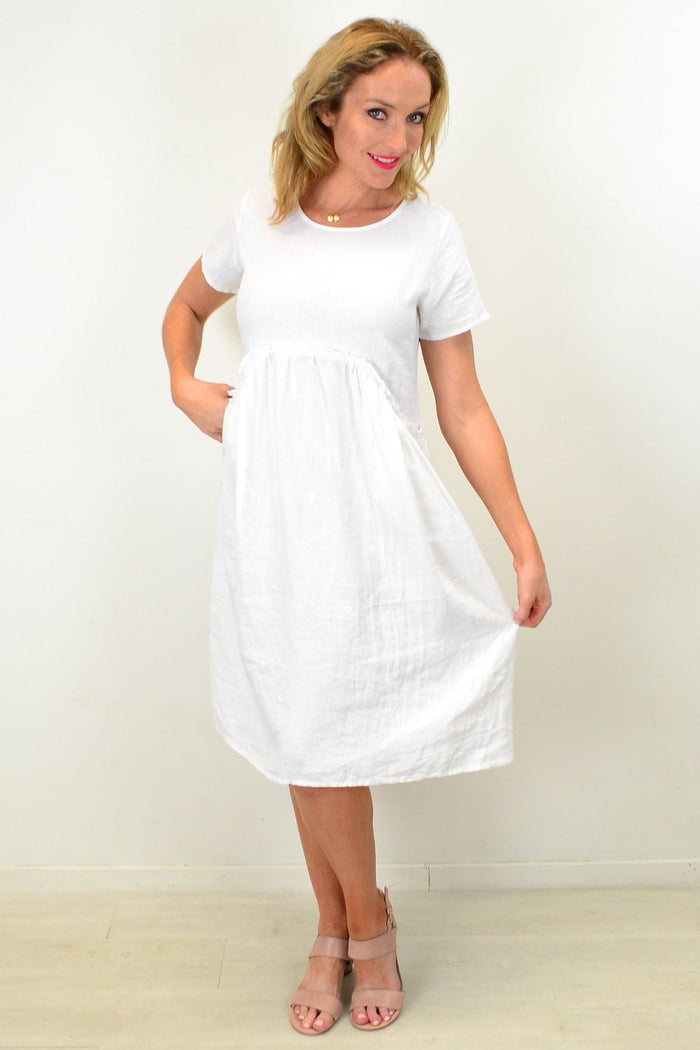 White linen Sunday best tunic dress by Cali&Co, featuring a relaxed fit and classic design, shown hanging on a wooden hanger.
