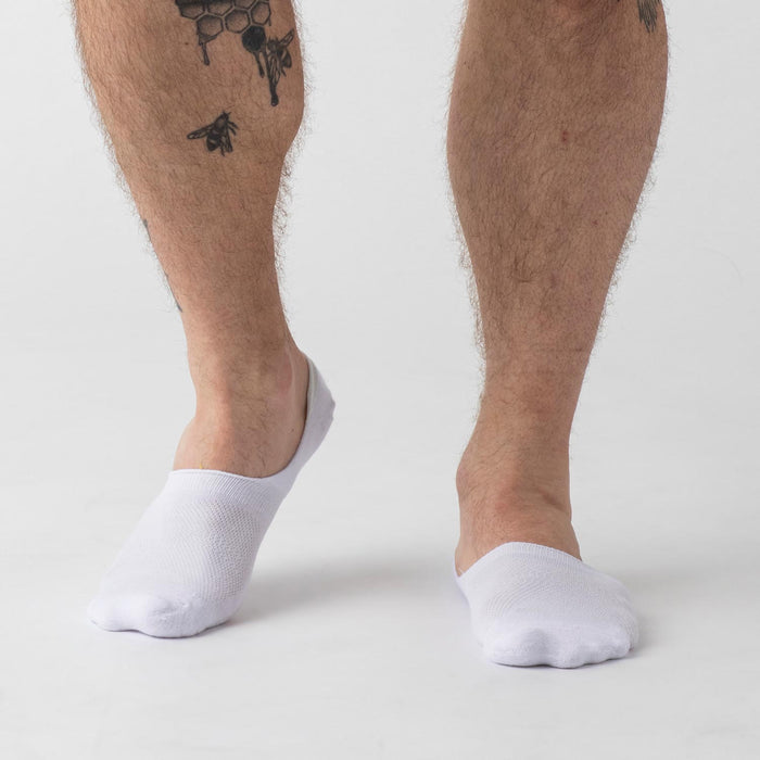 White Never Show Socks 6-Pack on tattooed calf, featuring seamless toe.