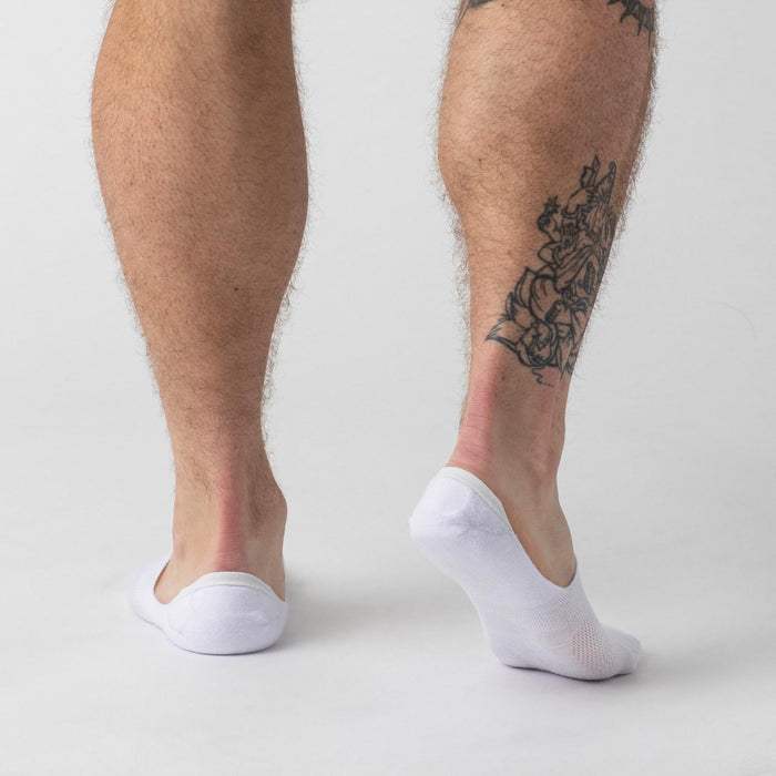 White Never Show Socks 6-Pack on tattooed legs, showcasing low-cut design.